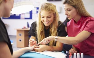 Photo of Cosmetology Student doing nails on a client with instructor helping